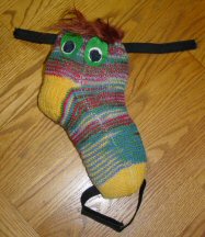 Low Tech project- Pillar Buddy is a sall stuffed pillow made from a sock. It is decorated with hair and eyes and is used to position a switch device or an Augmentative Communication device.