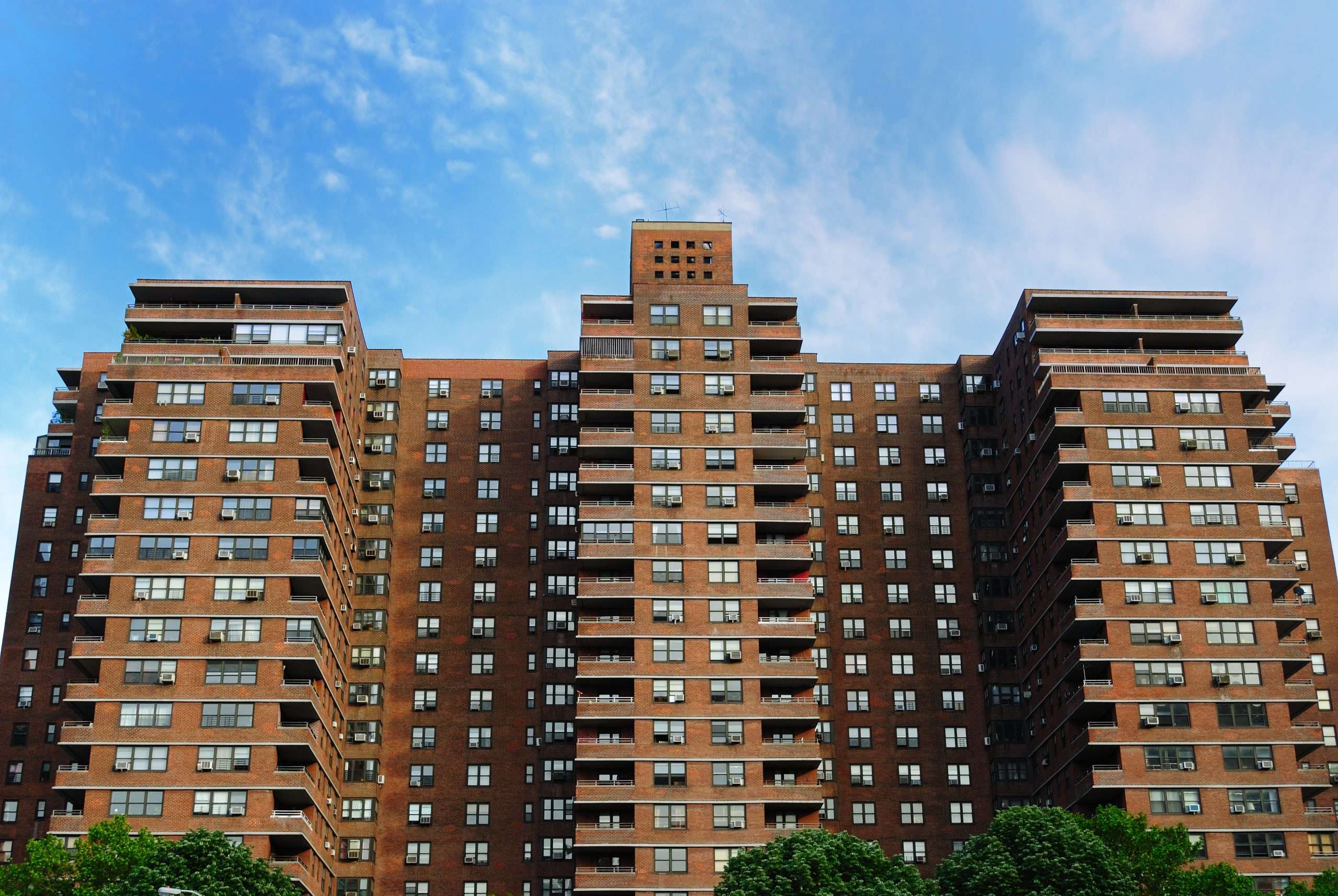 A large brick apartment complex in New York City against a blue sky