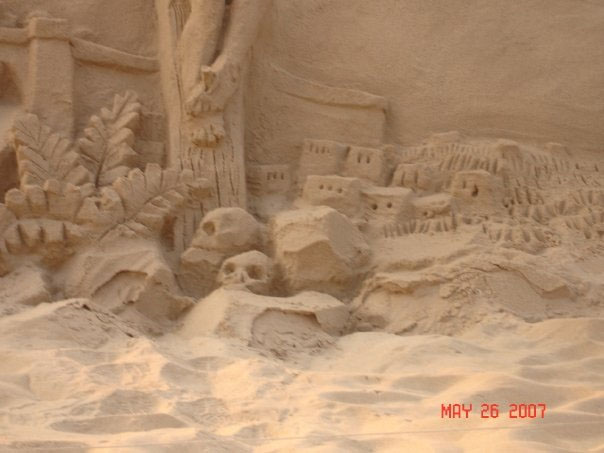 Sand Sculpture created at some beach. The sand sculpture has skulls at the bottom of someones feet.