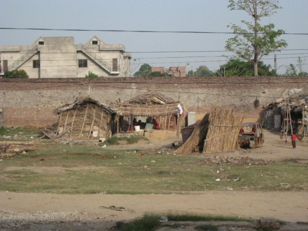 A group of women shaded by straw walls in Pakistan.