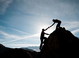 Picture of someone offering a helping hand Two people helping each other climb a mountain